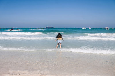 Rear view of woman on beach against sky