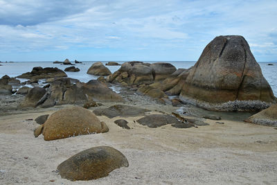 Scenic view of beach against cloudy sky