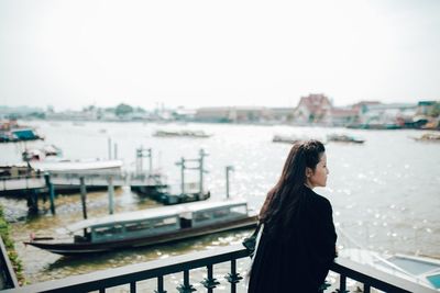 Young woman standing at harbor against clear sky