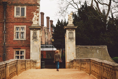 Rear view of woman walking towards building gate