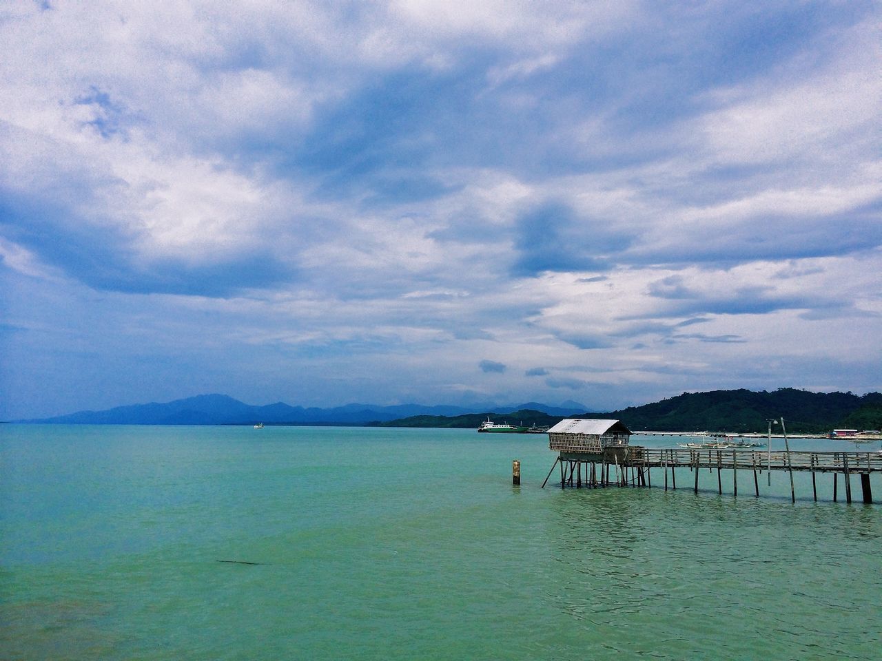 sky, water, tranquil scene, cloud - sky, tranquility, scenics, sea, pier, cloudy, beauty in nature, cloud, nature, built structure, mountain, beach, idyllic, outdoors, day, non-urban scene, lake