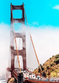 Cars moving on golden gate bridge against blue sky during sunny day