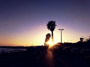 Silhouette street against sky during sunset