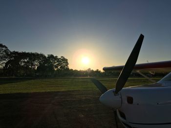 Airplane on field against sky during sunset