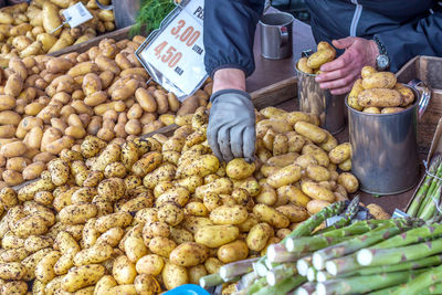 Midsection of vendor by potatoes at market stall