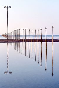 Wooden posts in sea against clear sky