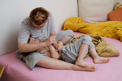 Mother having fun with son on bed. mom and toddler playing, tickling a child, laughing in the