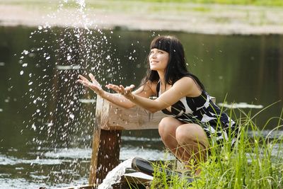 Young woman by lake splashing water