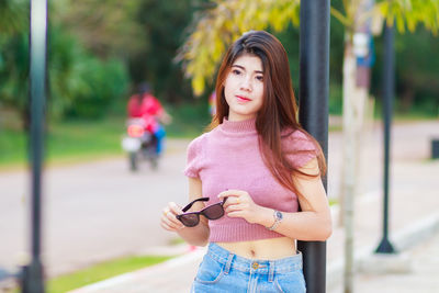 Portrait of young woman using phone while standing outdoors