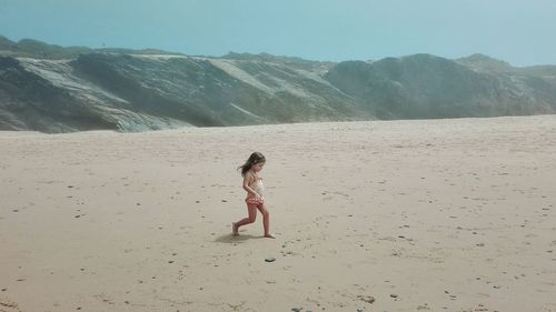 Full length of girl standing on sand at beach