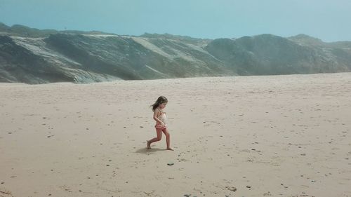 Side view of girl walking at sandy beach