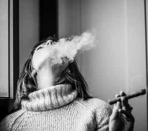 Portrait of woman holding cigarette at home