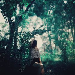 Mid adult woman sitting amidst plants in forest