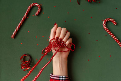 Cropped hand of woman holding bead over green background