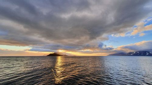 Scenic view of sea against dramatic sky during sunset