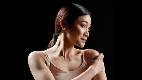 Young woman looking away against black background