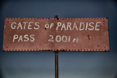 Close-up of road sign against sky