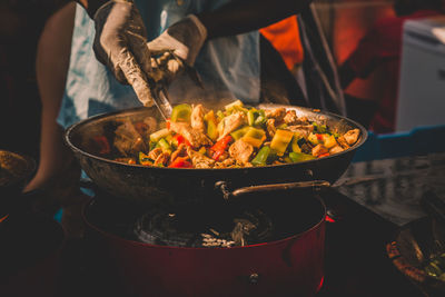 Midsection of man mixing food in wok