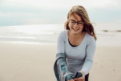 Beautiful young woman on beach against sky