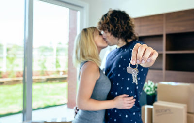 Man holding key ring while kissing with woman at home