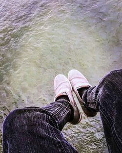 Low section of man sitting by sea