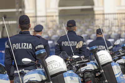 Rear view of police force standing by motorcycles