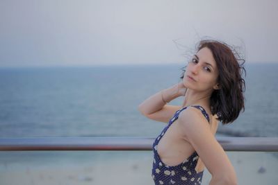 Portrait of beautiful young woman standing against sea