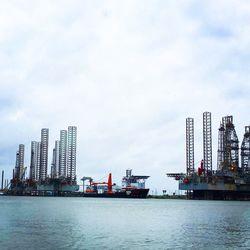 Cranes at commercial dock against sky