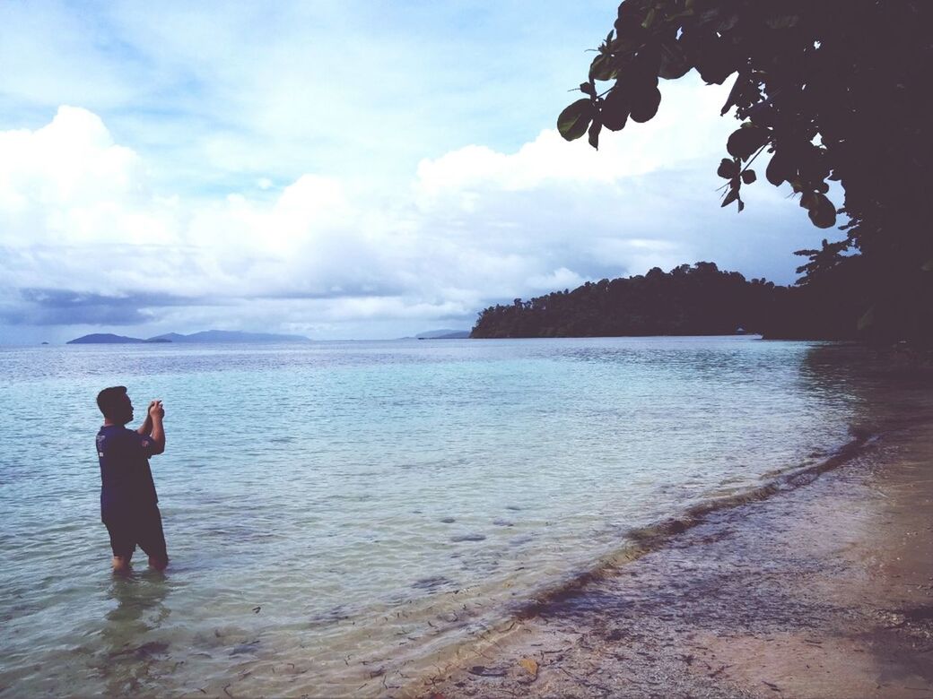 sky, water, leisure activity, lifestyles, cloud - sky, scenics, sea, mountain, tranquil scene, tranquility, beauty in nature, standing, beach, rear view, nature, cloud, full length, vacations