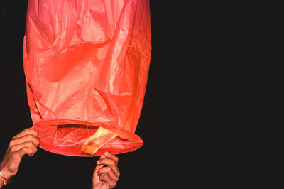 Cropped hands of person holding lantern against black background