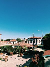 Houses by swimming pool in city against clear blue sky