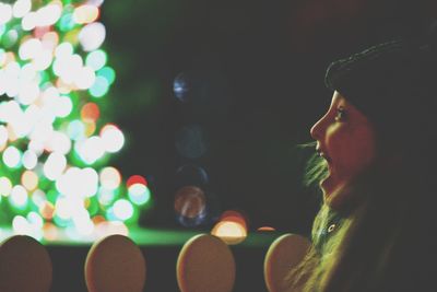 Close-up portrait of young woman looking away at night