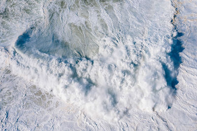 High angle view of waves breaking against sea