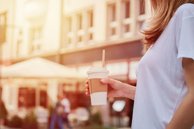 Woman holds paper coffee cup at city street