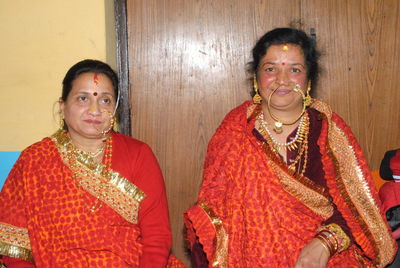 Women in traditional clothing sitting against wall