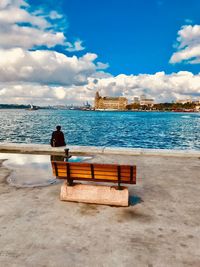 Rear view of man sitting on bench in sea