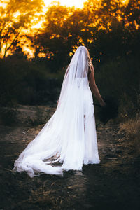 Rear view of woman with umbrella standing against trees