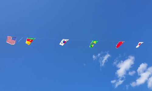 Low angle view of flags hanging against blue sky