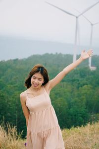 Happy woman standing on field against sky