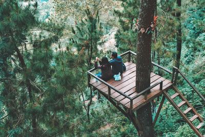 High angle view of man and woman sitting on observation point in forest