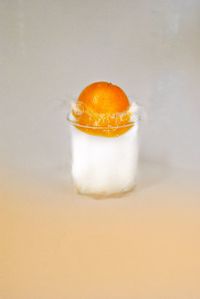 Close-up of orange slice on table against white background