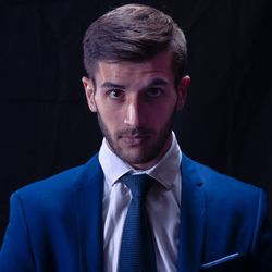 Thoughtful young man sitting on chair against black background