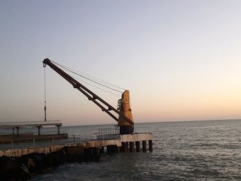 Pier over sea against clear sky during sunset