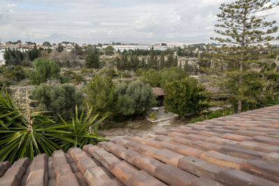 View of trees and buildings against cloudy sky