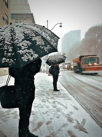 People walking on wet street in city during winter