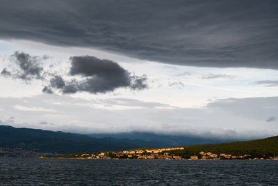 Scenic view of sea by mountains against sky