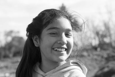 Close-up portrait of smiling girl against sky