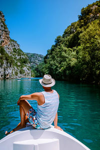 Rear view of man sitting on boat in lake