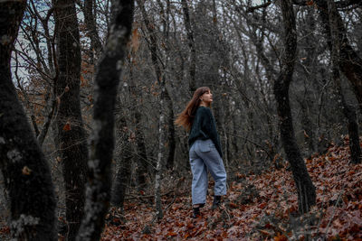 Low angle view of woman hiking in forest during autumn