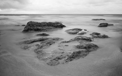 Scenic view of rocks on sea against sky